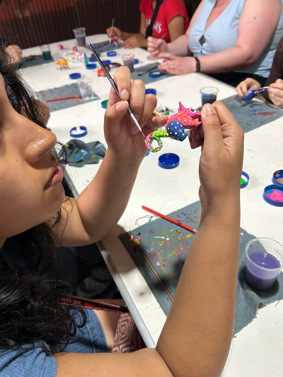 Visitantes pintando alebrijes